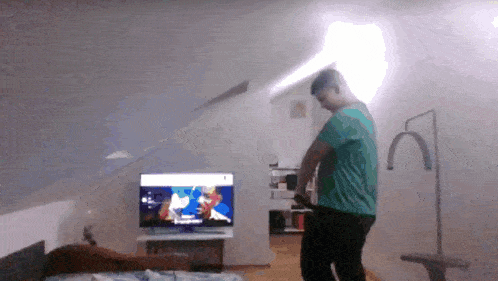 a man in a green shirt is standing in front of a television with a cartoon on it