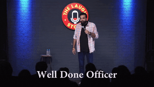 a man stands on a stage in front of a sign that says " well done officer "