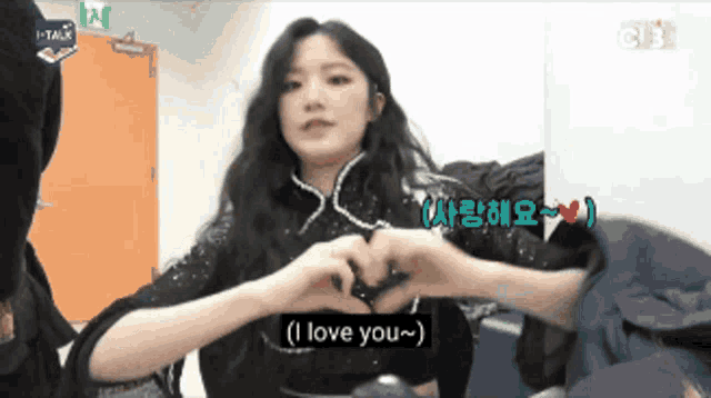 a woman making a heart shape with her hands and the words i love you
