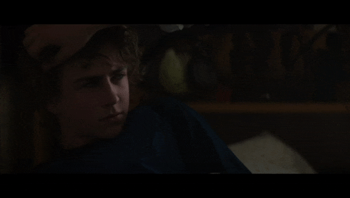 a young man laying on a bed with his hand on his head