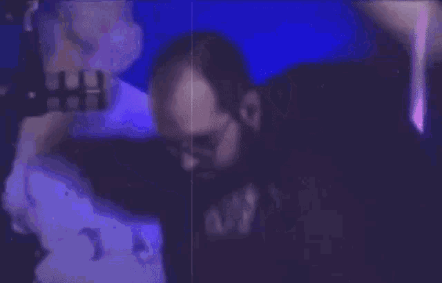 a blurry picture of a man raising his arms in the air in a dark room .