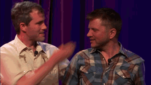 a man in a plaid shirt talks to another man