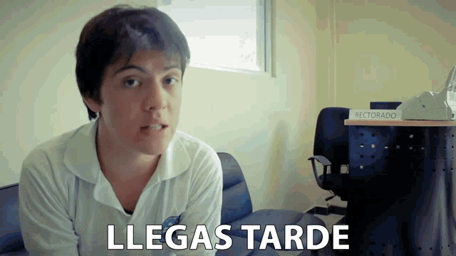 a man in a white shirt stands in front of a desk that says rectorado