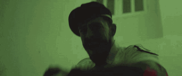 a man in a beret is holding a flashlight in a dark room