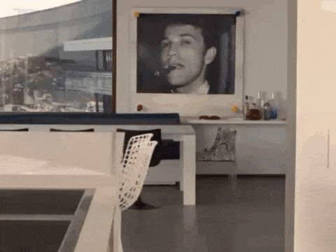 a picture of a man smoking a cigar is hanging on a wall in a living room .