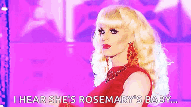 a drag queen is wearing a red dress and earrings and saying `` i hear she 's rosemary 's baby ... ''