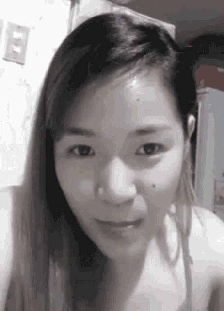 a close up of a woman 's face with a light switch on the wall behind her