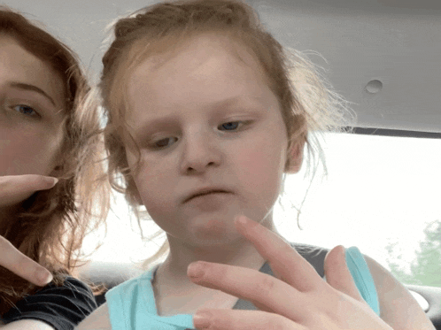 a little girl in a blue tank top is being held by her mother