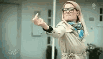 a woman in a trench coat and scarf is giving the middle finger .