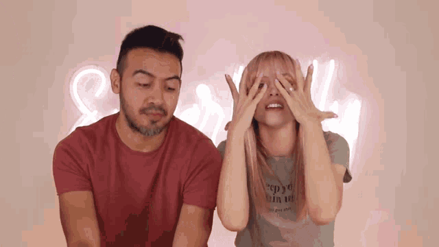 a man and a woman covering their eyes with their hands in front of a sign that says sally