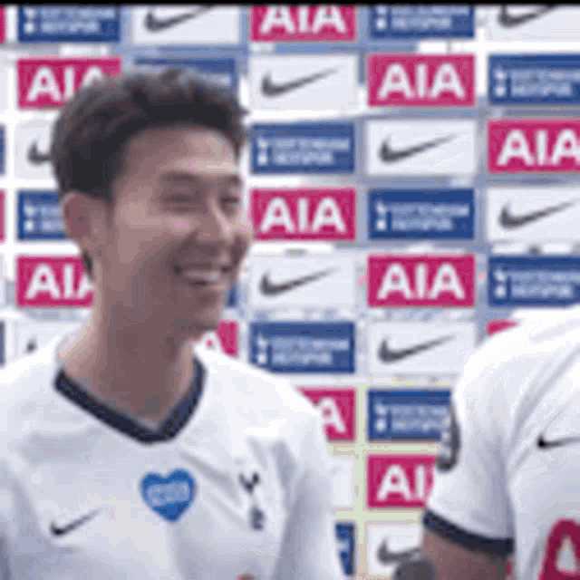 a man in a white shirt is smiling in front of a wall with aia logos .