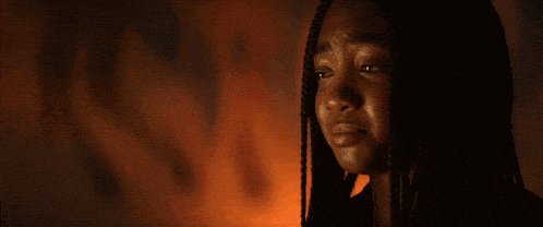 a close up of a woman 's face with fire behind her