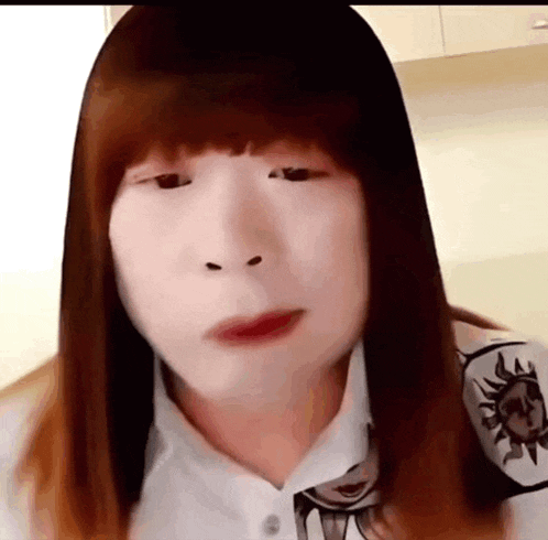 a woman with long hair and a white shirt is making a funny face with her eyes closed .