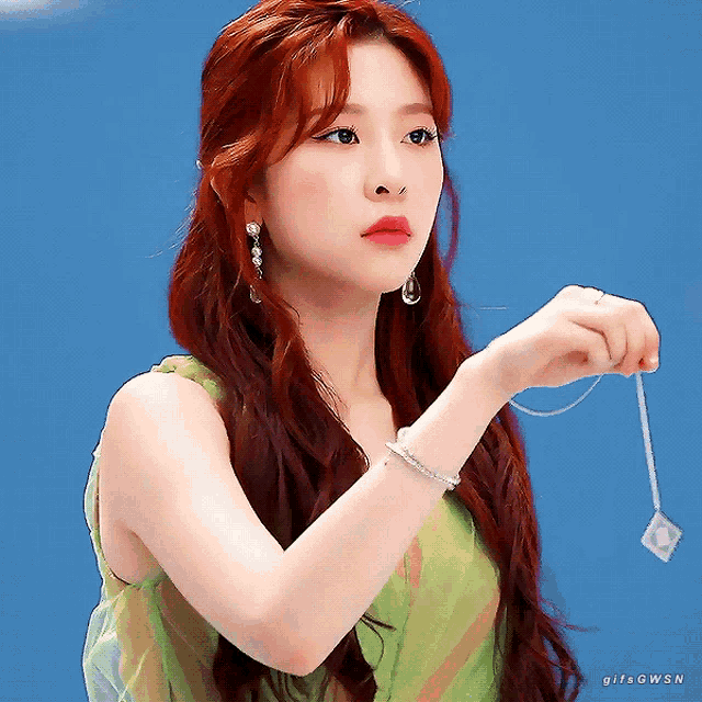 a woman with red hair is wearing a green dress and a bracelet on her wrist