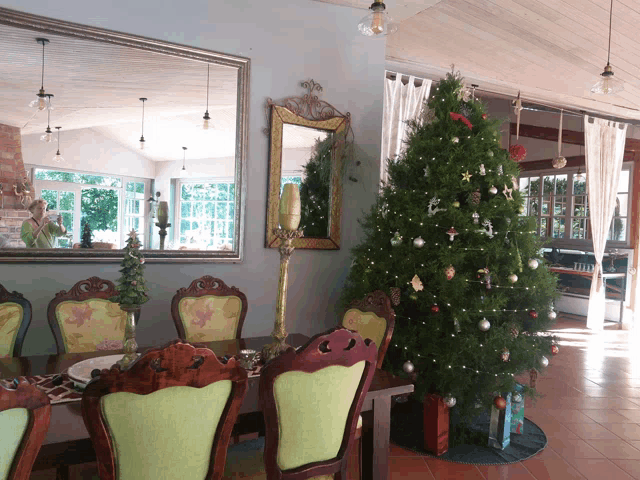 a dining room with a christmas tree and a large mirror