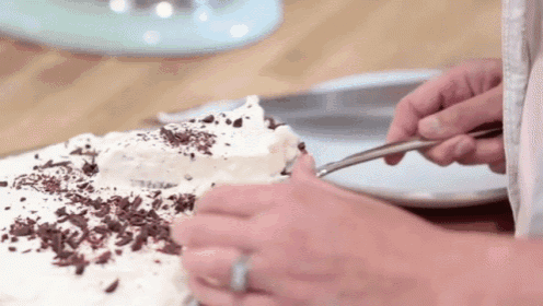 a person is cutting a piece of cake with chocolate shavings on top .