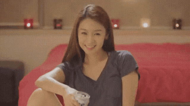 a woman is sitting on a bed holding a can of soda