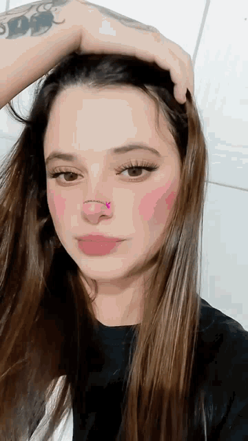 a woman with a tattoo on her arm has a nose ring on her nose