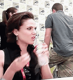 a woman sitting at a table with a lanyard around her neck that says comic con on it