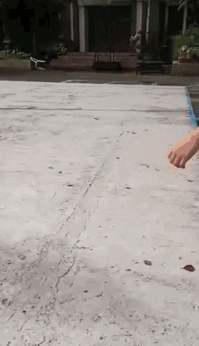 a person is standing on a concrete surface with their hand in the air .