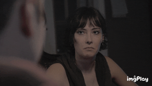 a woman sitting in a dark room with the word imgplay on the bottom