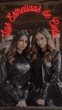 two women are standing next to each other under a neon sign that says las estrellas de eilia