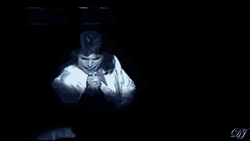 a man is singing into a microphone on a stage in a dark room .