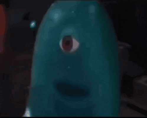 a close up of a blue monster with a red eye in a dark room .