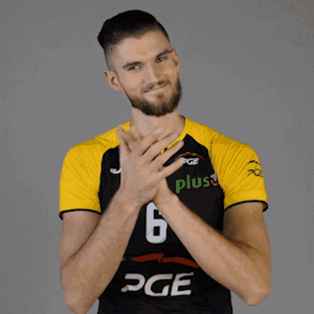 a man wearing a black and yellow pge jersey is clapping his hands