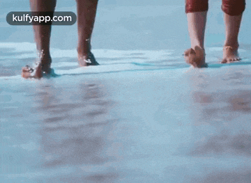 a man and a woman walking barefoot on the beach .