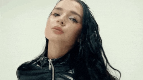 the woman is wearing a black leather jacket and looking at the camera .