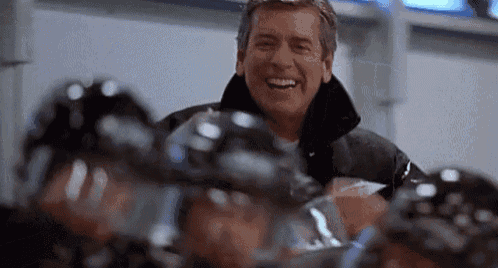 a man is laughing while standing in front of a group of hockey players .
