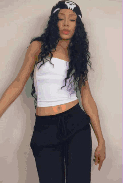 a woman wearing a white crop top and black pants