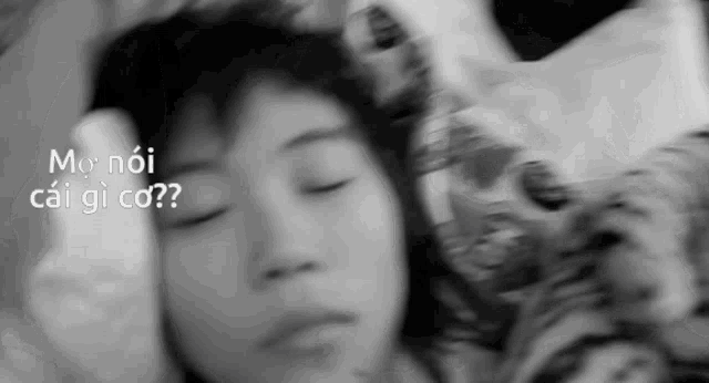 a black and white photo of a person sleeping with the words mo noi cai gi co written above them