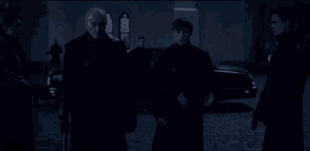 a group of men standing in front of a car in the dark