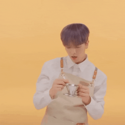 a man wearing an apron is holding a cup of coffee