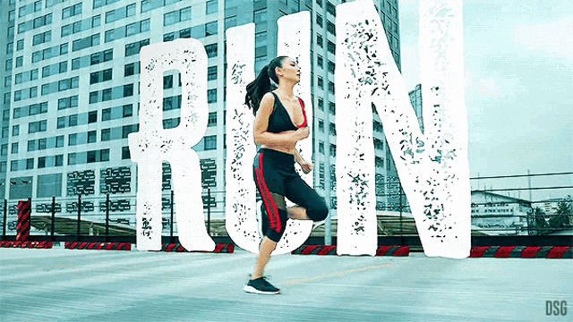 a woman is running in front of a large white sign that says run