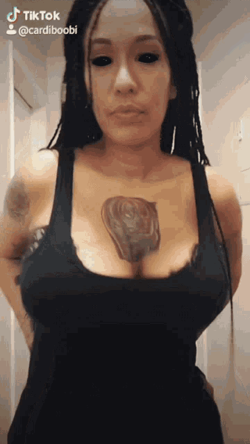 a woman with black eyes and a tattoo on her chest has a tiktok account named cardiboobi
