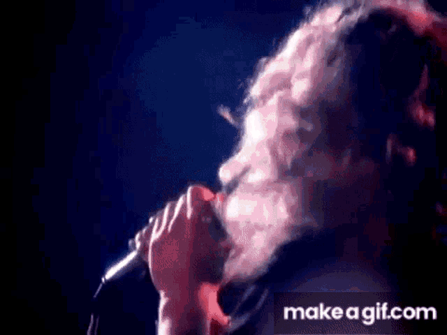 a man with a beard is singing into a microphone on make a gif.com .