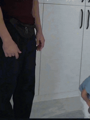 a man in a red shirt is standing next to a woman in a blue shirt sitting on a toilet .