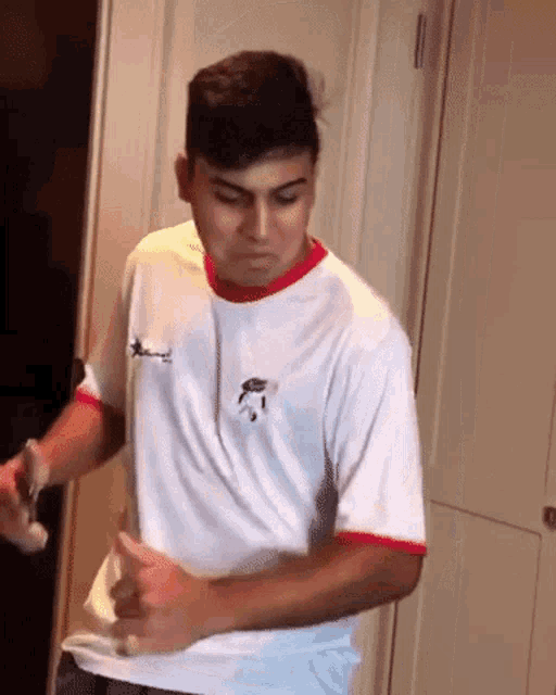 a young man wearing a white shirt with a red stripe on the sleeve