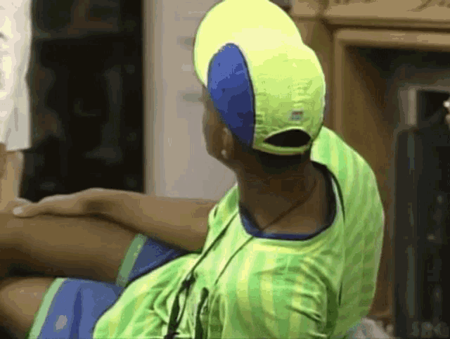 a person wearing a green shirt and a yellow hat is sitting down