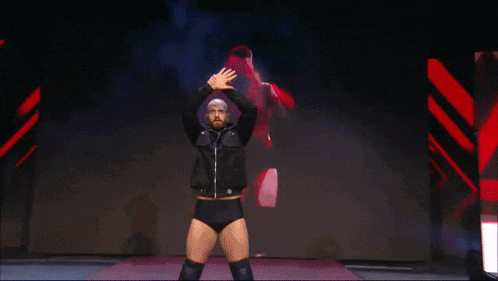 a man in a black jacket stands on a stage with his hands in the air in front of a sign that says rxr
