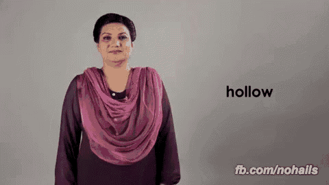 a woman wearing a pink scarf is signing the word hollow