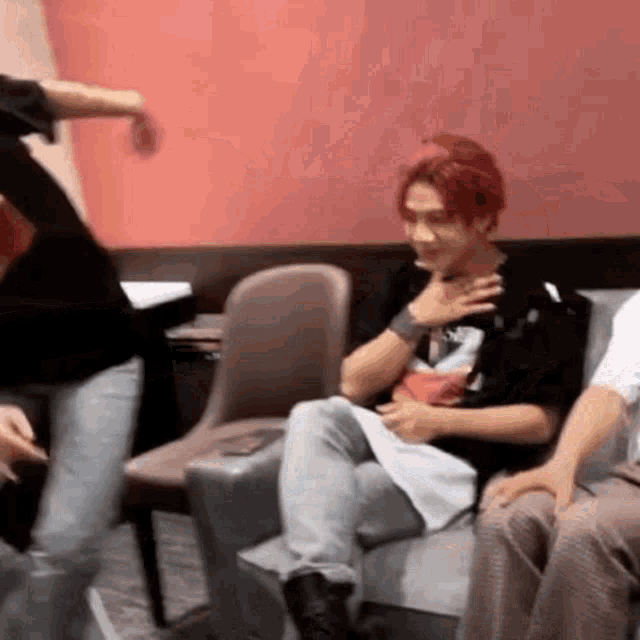 a man with red hair is sitting on a couch in a room .