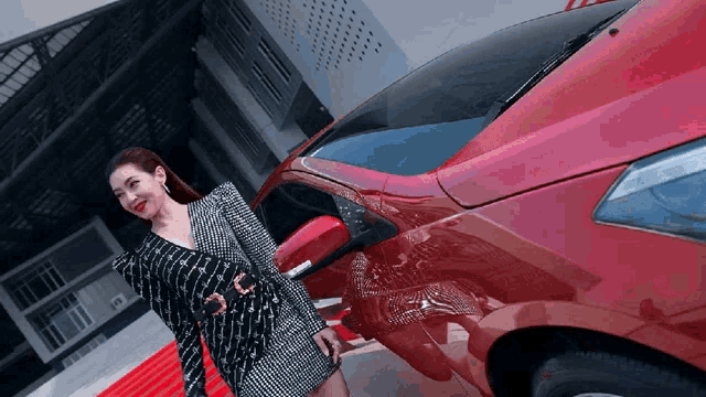 a woman in a black and white dress stands next to a car