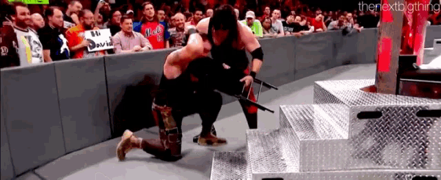 a wrestler is kneeling down in front of a crowd while holding a gun ..