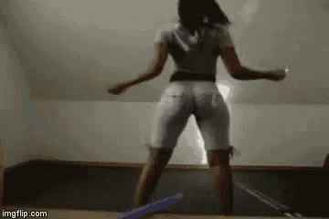 a woman is dancing in a room with a purple object in the background .