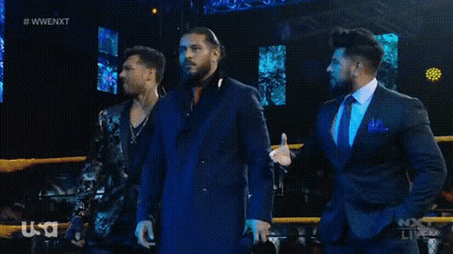 three men in suits are standing next to each other in a ring .