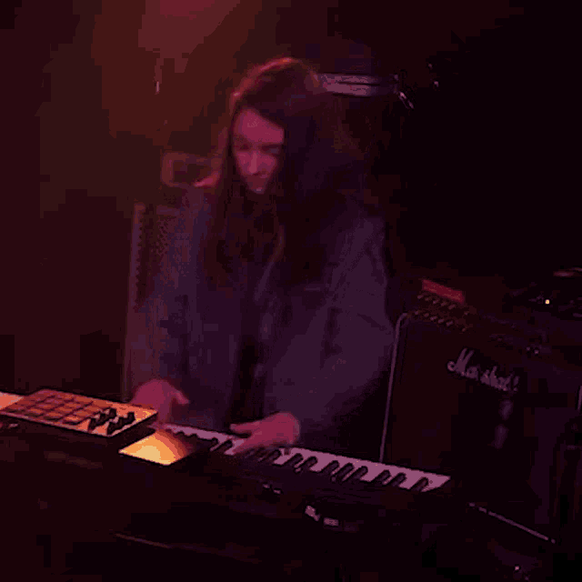 a woman playing a keyboard in front of a marshall amp